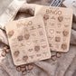 two wooden bingo cards with various heart-shaped charms attached to them, placed on a soft, furry surface.