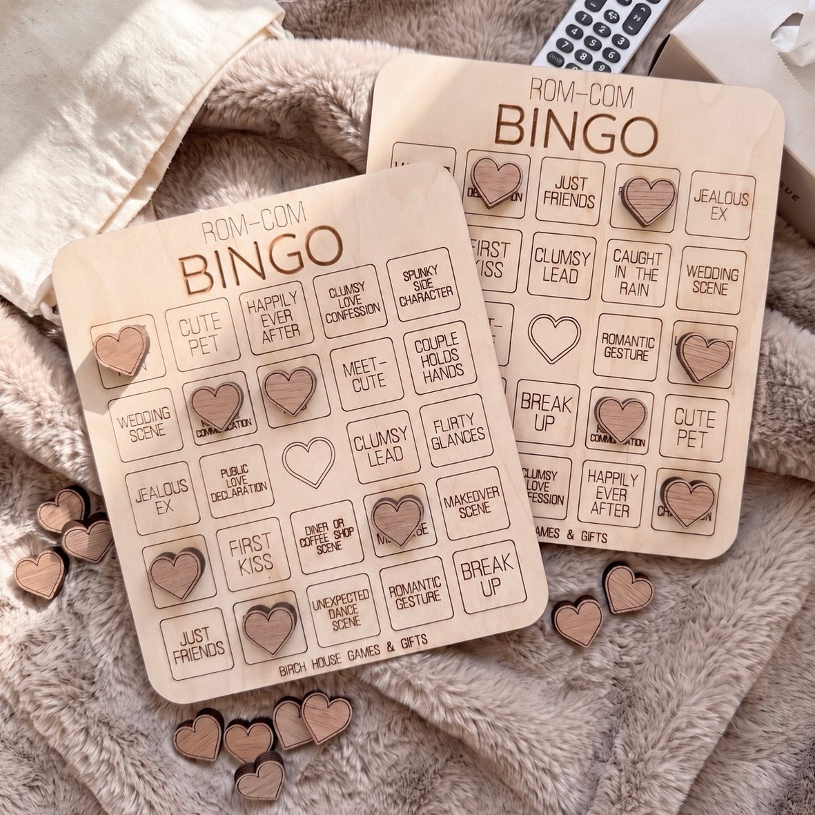 two wooden bingo cards with various heart-shaped charms attached to them, placed on a soft, furry surface.