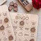 a wooden bingo board with various phrases and a remote control on a table.