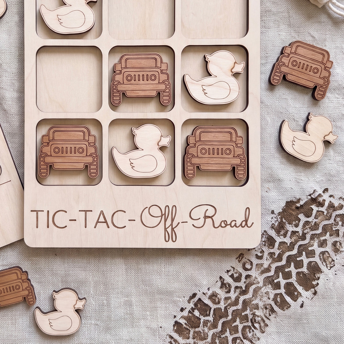 a wooden tic-tac game with a car and rubber duck motif, along with a footprint on the ground.