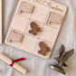 a wooden tic-tac game board with wooden eagle tiles, a rolled-up diploma, and a metal eagle figurine.