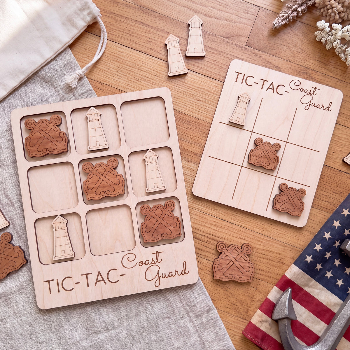 a wooden game board labeled "TIC-TAC-Coast Guard" and several wooden pieces with lighthouse designs, arranged on a wooden surface.