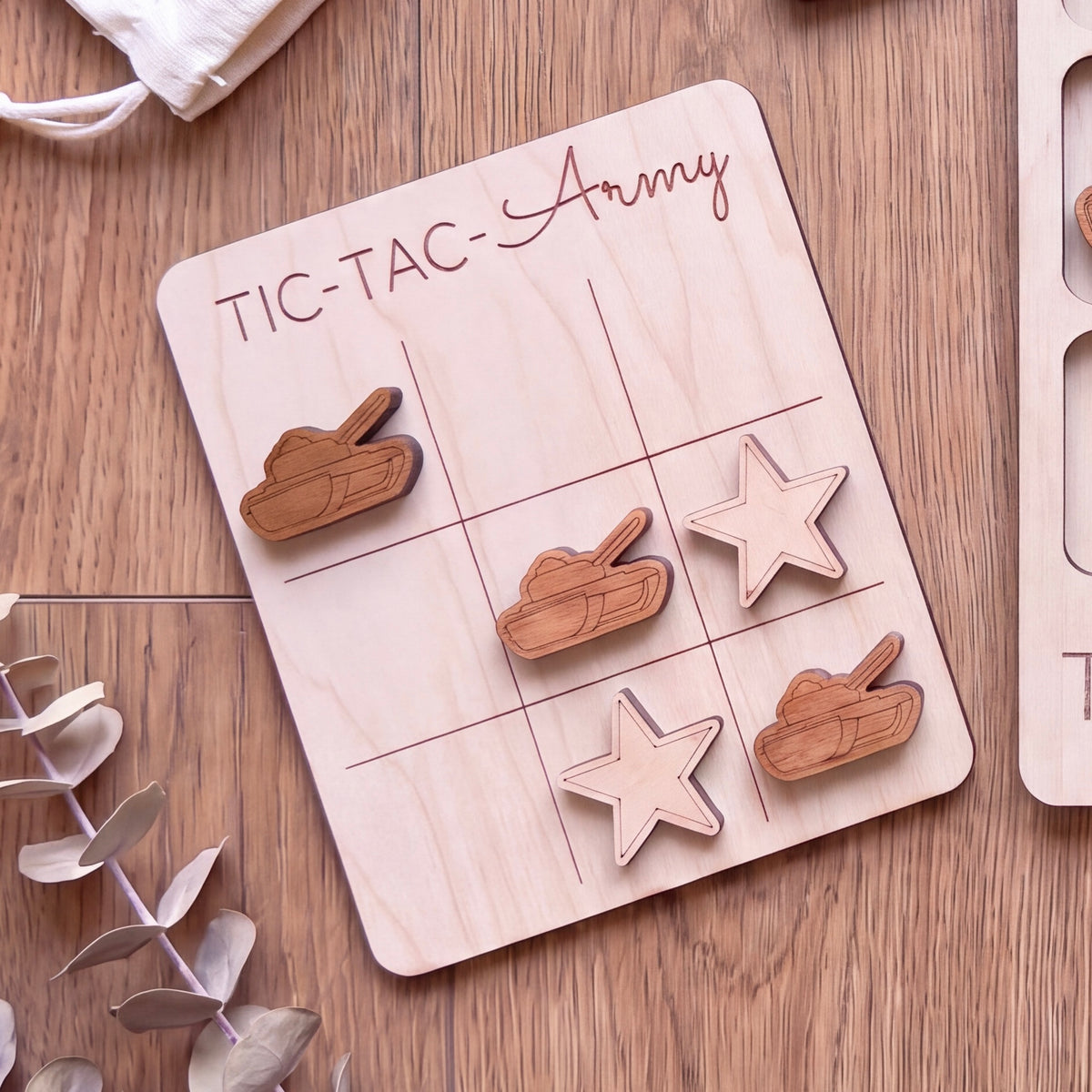 A wooden tic-tac-toe game board with wooden tiles and wooden game pieces, including a tank and a star, placed on a wooden surface.