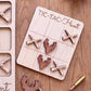 a wooden tic-tac hunt game with deer heads and crossed guns as game pieces, placed on a wooden surface alongside a bullet.