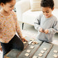 Two young children, a girl and a boy, are playing with wooden blocks on a table.