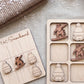 a wooden snowboard-themed game board and a wooden snowboard with various snowboarder icons, all placed on a beige fabric surface.