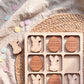 A wooden tic-tac-toe game with Easter-themed tiles, featuring wooden Easter eggs and bunnies.