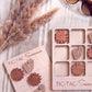 a wooden tic-tac-toe game with wooden tiles and a wooden board, along with some decorative elements such as straw and sunglasses.