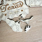 A wooden puzzle depicting the state of Texas, with pieces that represent the state's shape and a small piece that appears to be a horned animal.