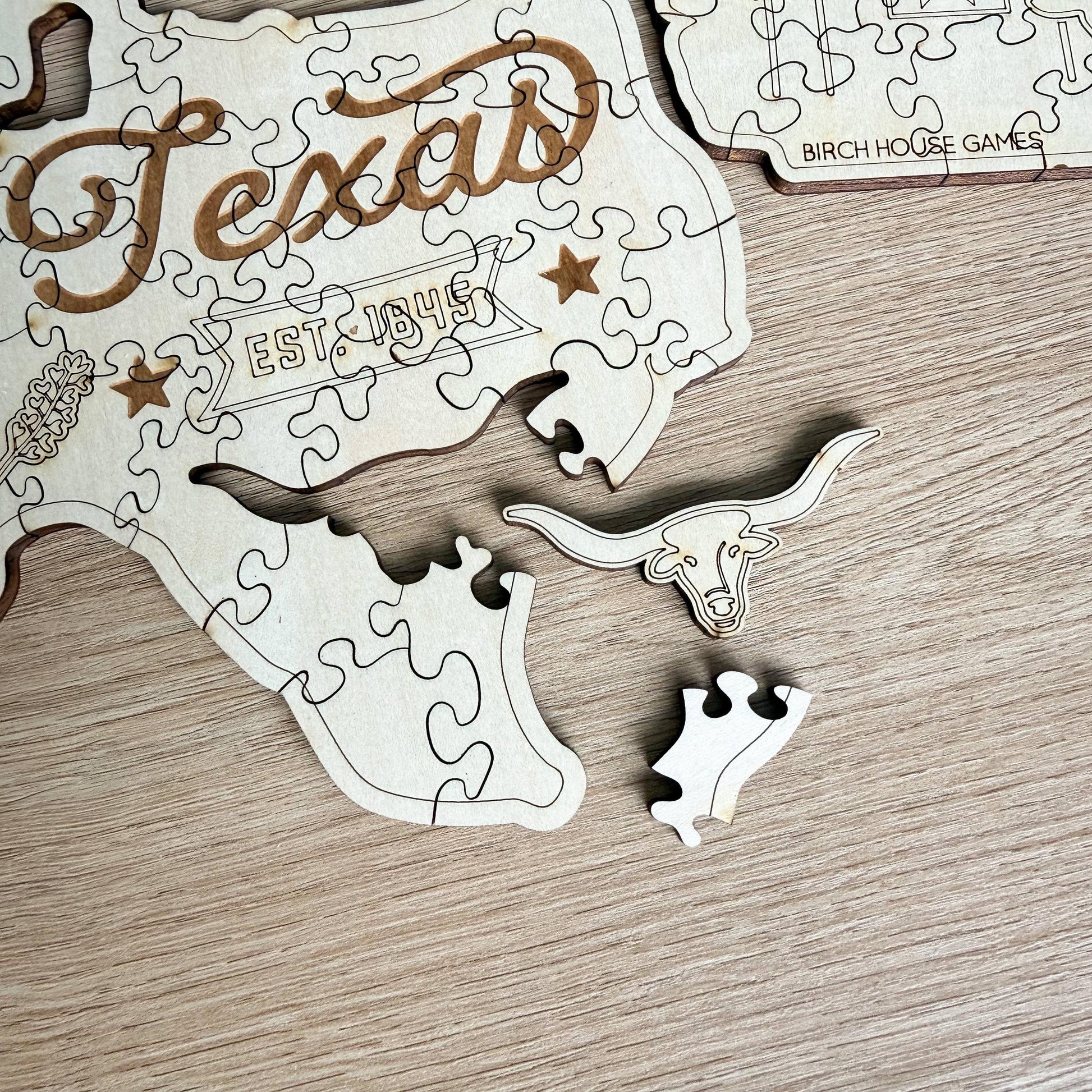 A wooden puzzle depicting the state of Texas, with pieces that represent the state's shape and a small piece that appears to be a horned animal.