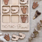 a wooden game board with dinosaur claw and tooth-shaped tiles, along with a few dinosaur claw and tooth-shaped tiles scattered around it.