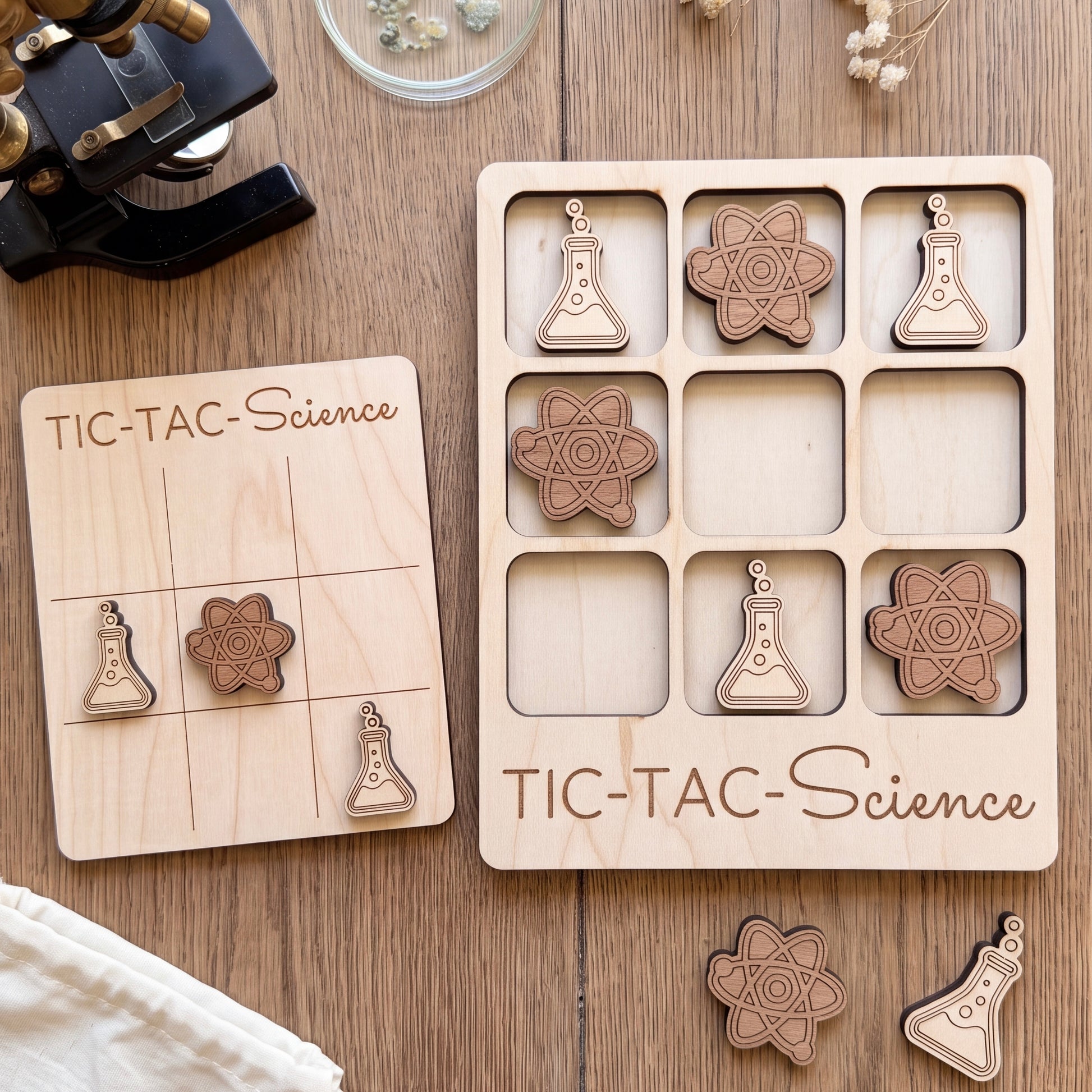 a wooden game board and a wooden puzzle with science-themed pieces, both placed on a wooden surface.