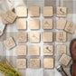 a collection of wooden puzzle pieces, each featuring various symbols and icons related to outdoor activities and camping, such as a compass, a tent, a lantern, a mountain, and a pair of binoculars.