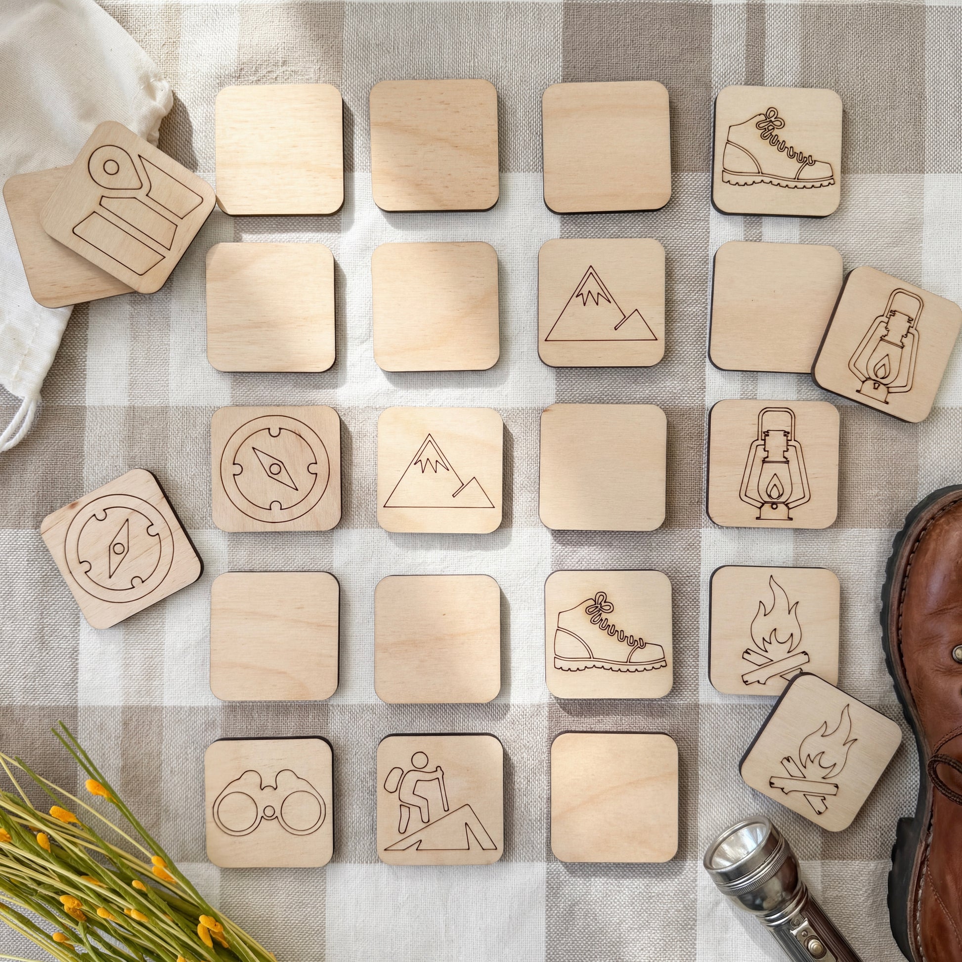 a collection of wooden puzzle pieces, each featuring various symbols and icons related to outdoor activities and camping, such as a compass, a tent, a lantern, a mountain, and a pair of binoculars.